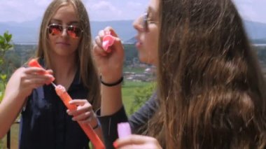 Yavaş çekimde kabarcıklar ile yaz aylarında dışarıda eğlenmek iki gençler Closeup