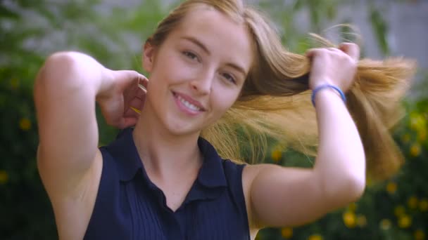 Une belle adolescente aux longs cheveux blonds sourit au ralenti — Video