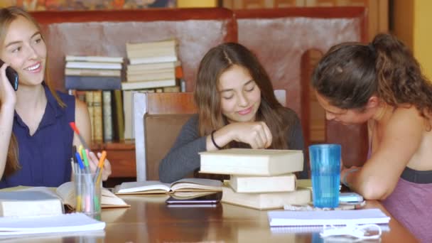 Een prachtige jonge blonde vrouw krijgt een telefoontje tijdens het studeren met vrienden — Stockvideo