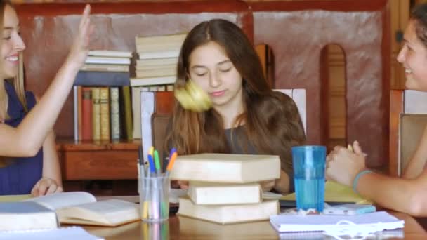 Teenage girls take a break from studying by throwing paper - dolly shot — Stock Video