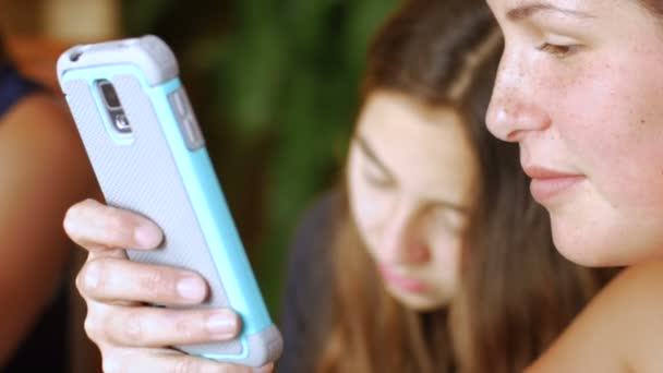 Trois jeunes belles étudiantes utilisent leur téléphone portable dans un groupe d'étude — Video