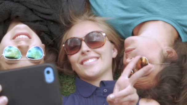 Three best friends take a selfie while lying next to each other on the grass — Stock Video