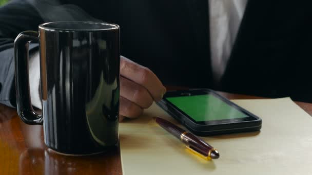 Closeup επιχείρηση άνθρωπος πίνει καφέ με κινητό τηλέφωνο πράσινη οθόνη — Αρχείο Βίντεο