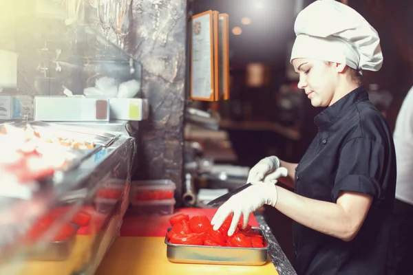 Piekarz kucharz w czarnym mundurze wprowadzenie pizzy w piecu z łopatą w kuchni restauracji — Zdjęcie stockowe