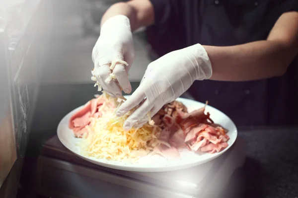 Kocken baker cook i svart uniform sätta pizza i ugnen med spade på restaurang kitchen — Stockfoto