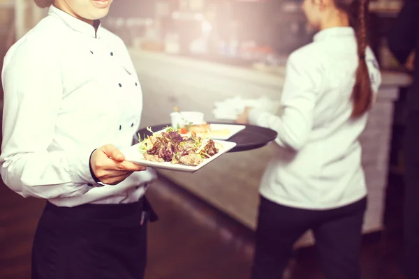 Официанты несут тарелки с мясным блюдом на свадьбе — стоковое фото
