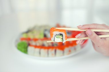 Yemek çubuklarını kapatın. Lokantada porsiyon suşi alın. Yemek çubuklarıyla suşi yiyin.