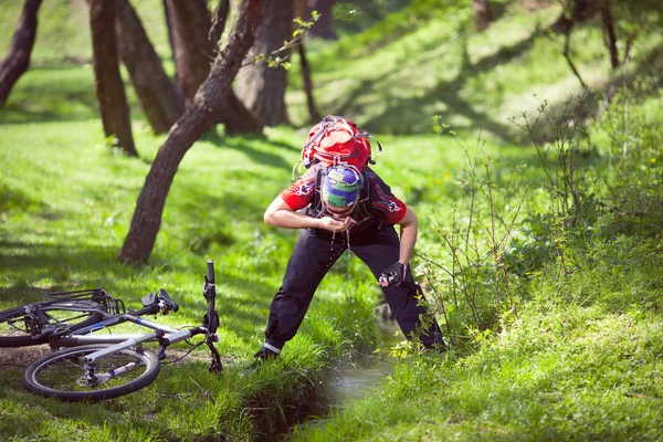Mountain biker pitnou vodu z pramene — Stock fotografie