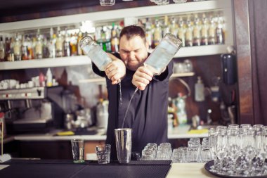 Barman hold bottle and pouring cocktail at the bar clipart
