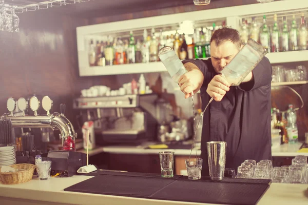 Barman hålla flaskan och hälla cocktail i baren — Stockfoto
