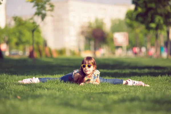 Κοπέλα φορώντας τα πατίνια που κάθεται στο γρασίδι στο πάρκο — Φωτογραφία Αρχείου