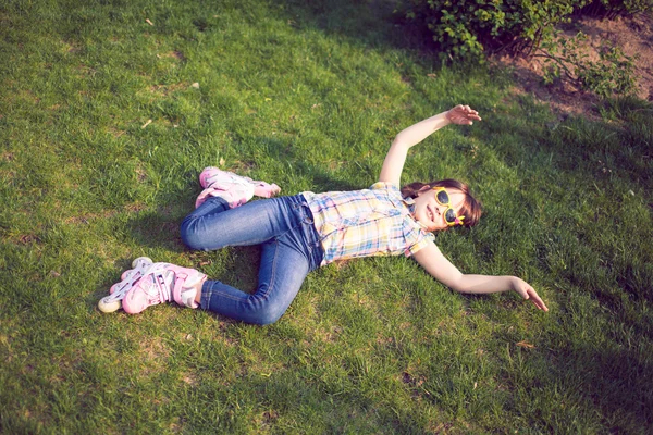 Mädchen mit Rollschuhen sitzt auf Gras im Park — Stockfoto