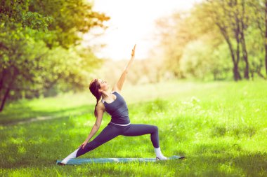 Sabah parkında yoga yapan genç bir kadın.