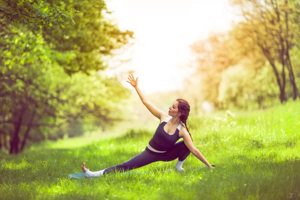 Mujer joven haciendo yoga en el parque matutino — Foto de Stock