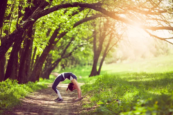 Mladá žena dělá jógu v ranním parku — Stock fotografie