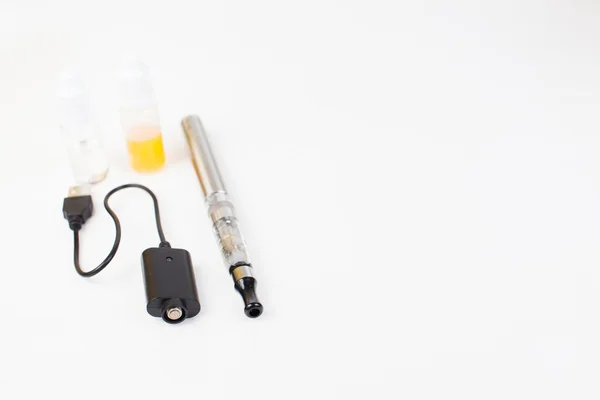 Inhalateur électronique de nicotine sur fond, bouteilles avec des liquides derrière l'inhalateur — Photo