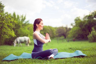 Sabah parkında yoga yapan genç bir kadın..