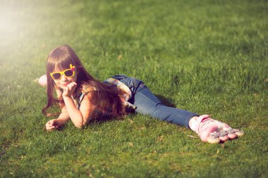 çim parkta oturan paten takan kız.