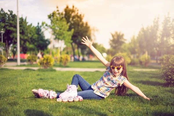 Девушка в роликовых коньках сидит на траве в парке . — стоковое фото