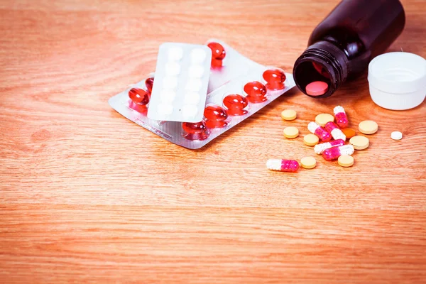 Pills in a bottle on wooden background, Medication for treatment — Stock Photo, Image