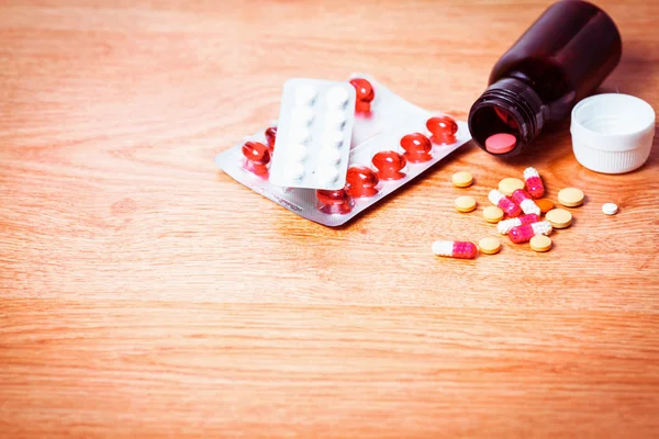 Pastillas en un frasco sobre fondo de madera, medicamentos para el tratamiento — Foto de Stock