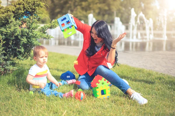 Criança jogar brinquedo com a mãe no parque feliz . — Fotografia de Stock