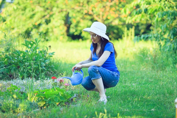 Ευτυχής ώριμη γυναίκα που φροντίζει τα λουλούδια στον κήπο. — Φωτογραφία Αρχείου