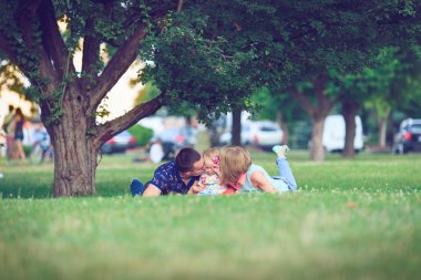Çimenlerin arasında yatan üç kişilik mutlu bir aile. Sıcak efekt eklendi.