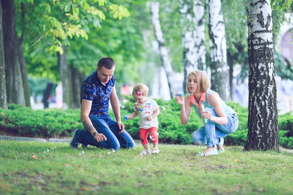 Happy family of three lying in the grass . Warm effect added. — Stock Photo, Image