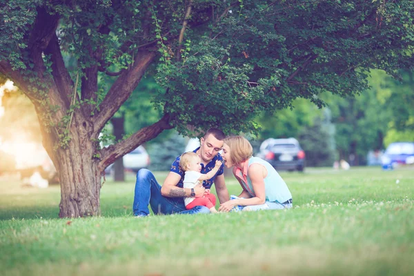 Gelukkige familie van drie liggen in het gras. Warm effect toegevoegd. — Stockfoto
