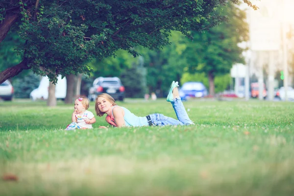 Gelukkige familie van drie liggen in het gras. Warm effect toegevoegd. — Stockfoto