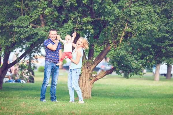 Feliz familia de tres tendidos en la hierba. Efecto cálido añadido . — Foto de Stock
