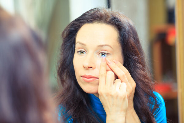 Close up of a woman putting contact lens in her eye