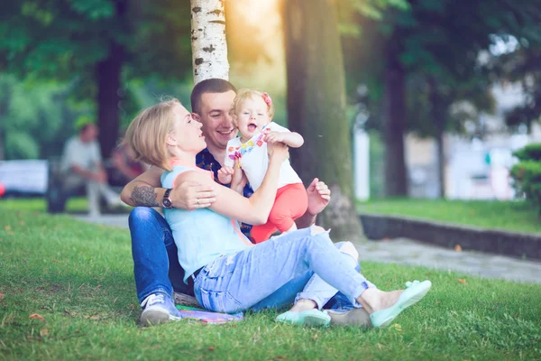 Família feliz de três deitado na grama  . — Fotografia de Stock