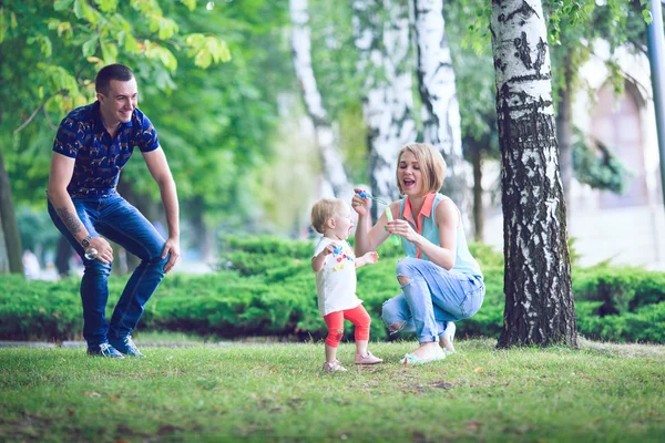 Happy family of three lying in the grass . — Stock Photo, Image