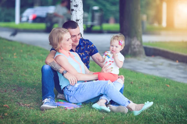 Lycklig familj av tre liggande i gräset . — Stockfoto