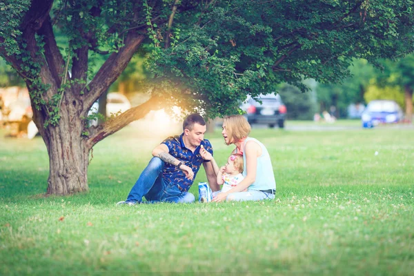 Heureuse famille de trois personnes allongées dans l'herbe  . — Photo