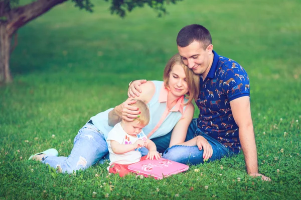 Lycklig familj av tre liggande i gräset . — Stockfoto