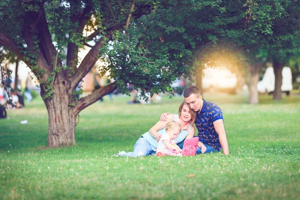 Šťastná rodina tří ležící v trávě . — Stock fotografie