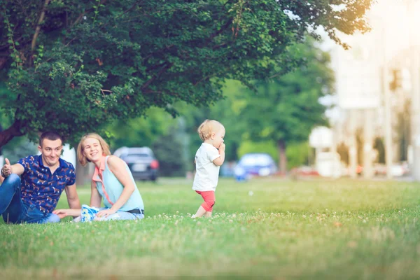 Gelukkig gezin van drie liggen in het gras . — Stockfoto