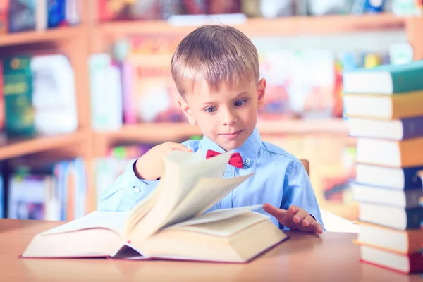 Schooljong geitje studeren in de bibliotheek, kind schrijven boek van de kopie papier in — Stockfoto