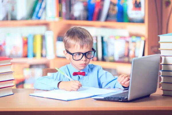 Schooljong geitje studeren in de bibliotheek, kind schrijven boek van de kopie papier in — Stockfoto