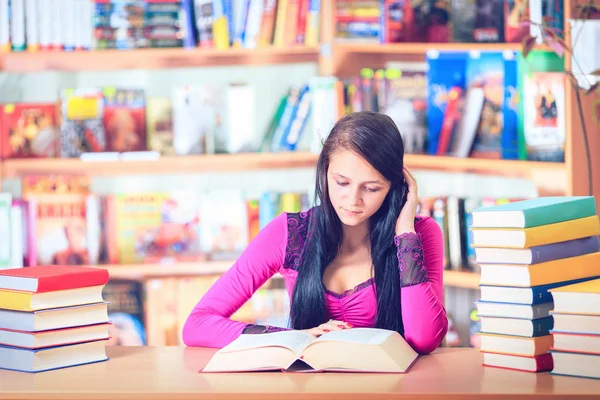 Estudante com óculos lendo livros na biblioteca — Fotografia de Stock