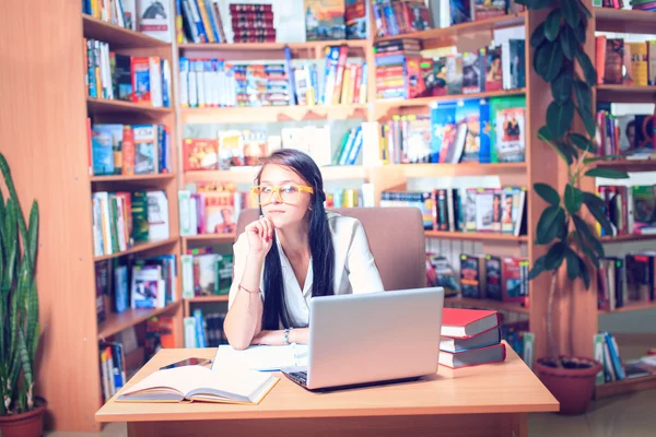 Estudante com óculos lendo livros na biblioteca — Fotografia de Stock