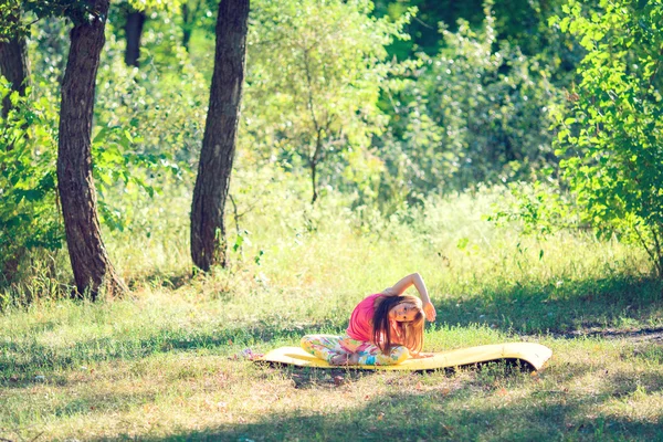 Yoga yapıyordum ve bir parkta çim siting tarafından rahatlatıcı genç — Stok fotoğraf