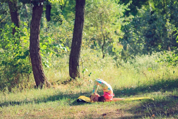 Teenager doing yoga and relaxing by siting in a grass in a park — Stock Photo, Image