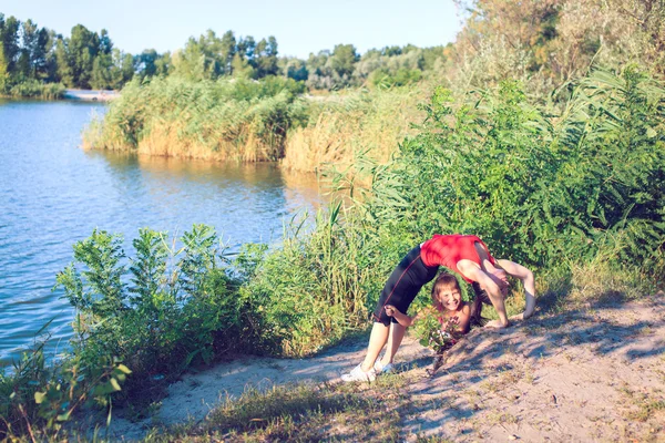 Familie workout - moeder en dochter doen oefeningen op strand. — Stockfoto