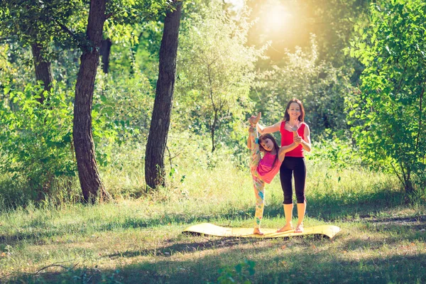 Familie workout - moeder en dochter doen oefeningen op strand. — Stockfoto