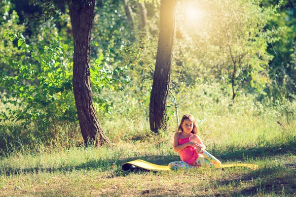 Dospívající dělá jógu a relaxaci u umístění na trávě v parku — Stock fotografie