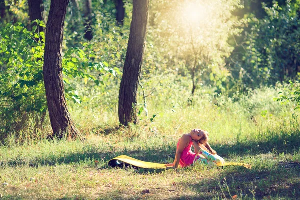 Tonåring gör yoga och koppla av placering i gräset i en park — Stockfoto